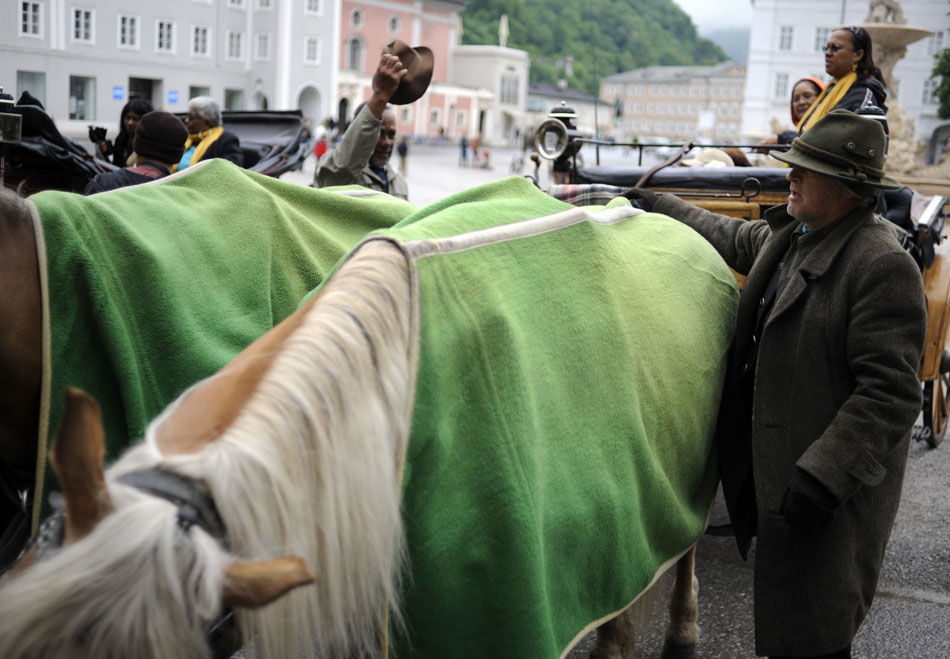 A horse carriage driver puts a blanket on his horse as he awaits customers on Friday, May 21, 2010, in the Old Town area of Salzburg, Austria.