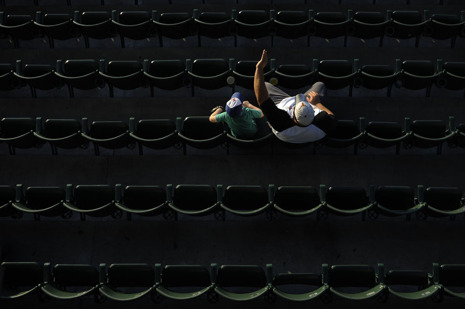 A man shields his eyes from the sun as he watches a minor league baseball game between Round Rock and Omaha at Dell Diamond in Round Rock on Monday, June 21, 2010. The two were some of the only fans to sit looking into the sun on the first base side before sundown.