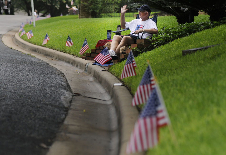 Rick Smith waves to participants in the Tarrytown Fourth of July Parade from the sidewalk in front of his home on Saturday, July 3, 2010.