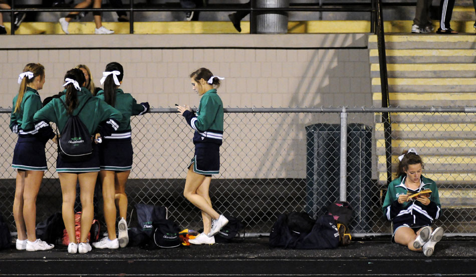 Peoria Notre Dame cheerleader Cassie Frow, right, reads "A Tale of Two Cities" by Charles Dickens during halftime in a game against Quincy Notre Dame on Thursday, Sept. 16, 2010, in Peoria. Frow was reading for a quiz on Friday morning.