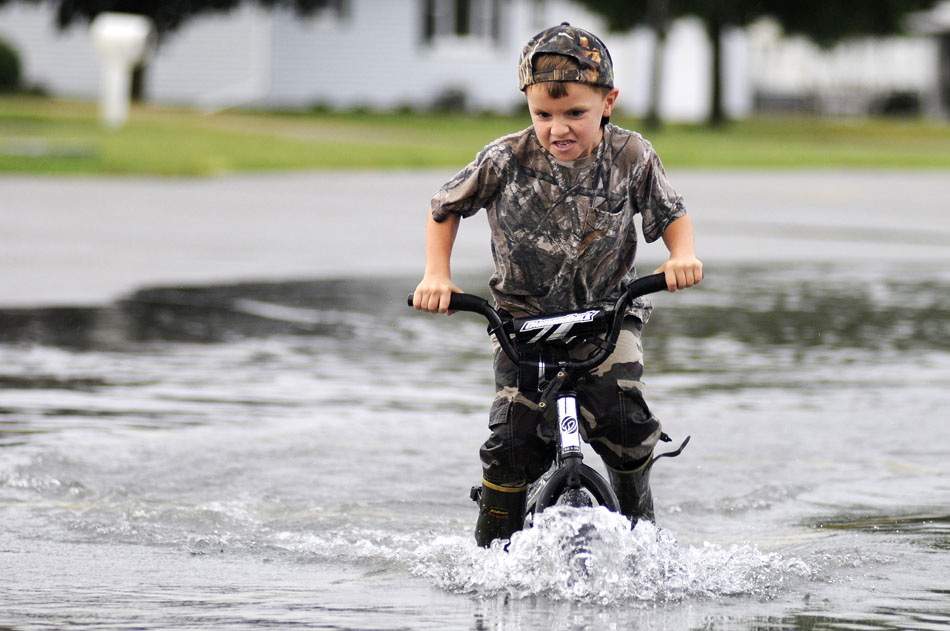 Jared Oest, age 6, navigates his bicycle through a large puddle of deep water with his brother, not pictured, on Thursday, Sept. 2, 2010, in a parking lot at Midwest Central High School in Manito, Ill. Several streets and parking lots in the village were flooded following a severe thunderstorm that pounded the area with high winds and heavy rain on Thursday afternoon.