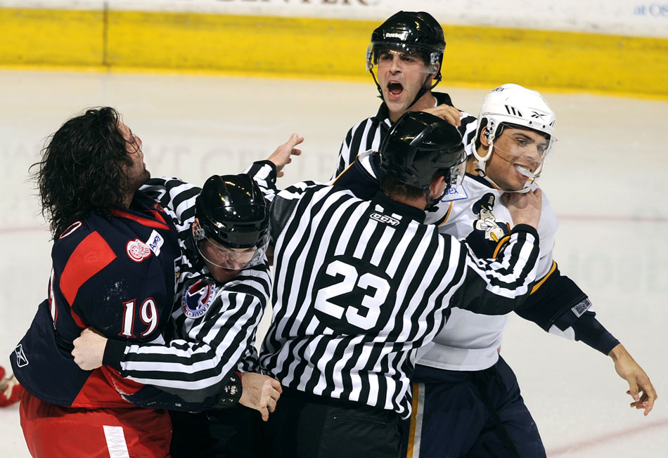 Referees separate Peoria Rivermen right wing Ryan Reaves, right, and Grand Rapids Griffins defender Greg Amadio (19) after a fight in the opening minutes of a game on Saturday, Dec. 11, 2010, at Carver Arena.