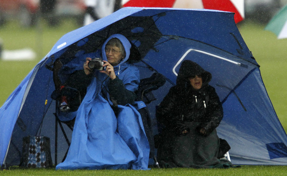 A fan looks to take a picture of the action from under an umbrella during a Class 4A boy's state soccer game on Friday, May 20, 2011, in Sheridan, Wyo.