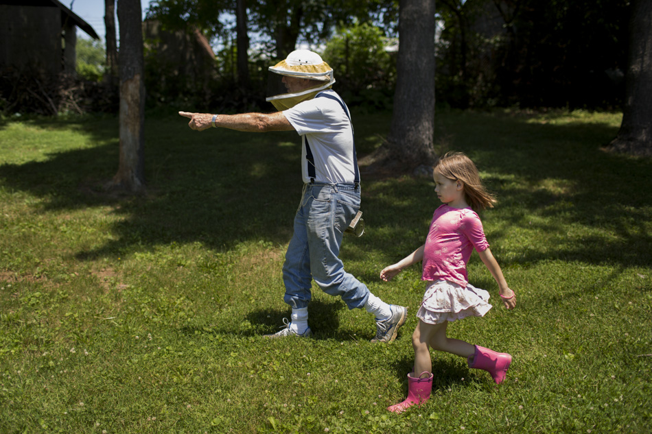 George Hegeman, an IU Professor Emeritus of Biology, leads Aurora Webeck, 7, to a beehive as he teaches her and other children, not pictured, about bees on Wednesday, June 10, 2015, at the Hilltop Garden and Nature Center. (James Brosher/IU Communications)