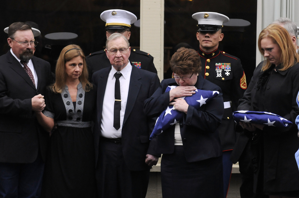 Debbie Kleinschmidt, second from right, the mother of Marine Sgt. Jeremy McQueary, holds a folded American flag after a ceremony remembering the life of her son on Sunday, Feb. 28, 2010, at The Seasons Lodge and Conference Center in Nashville, Ind. Pictured at right is McQueary's widow, Rae McQueary. The Columbus, Ind. native was killed in the Helmand Province in Afghanistan on Feb. 18.