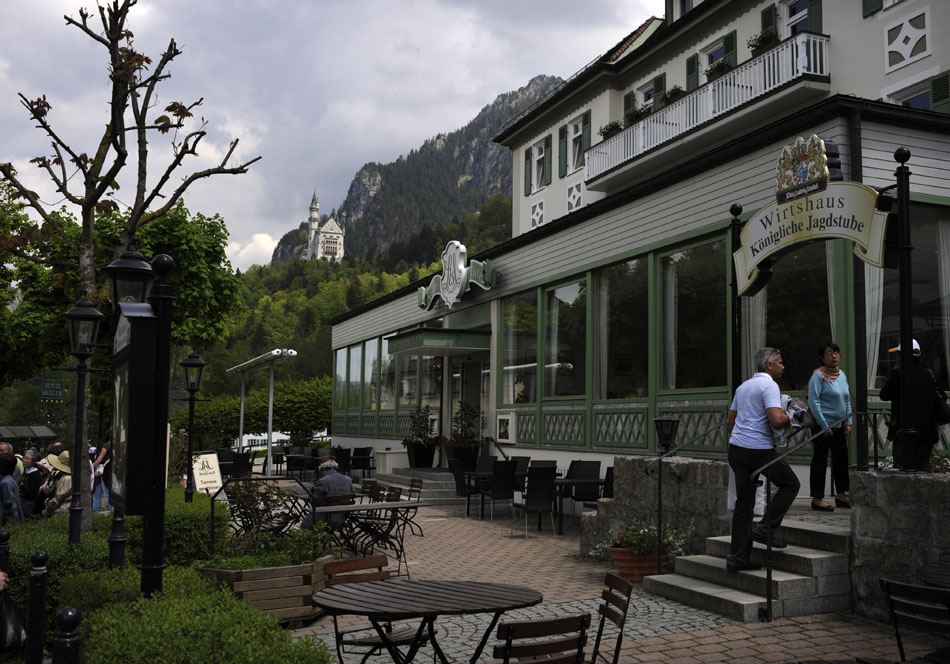 Tourists make their way into a traditional Bavarian beer garden within view of Schloss Neuschwanstein, middle, on Sunday, May 23, 2010, in Schwangau, Germany. The castle was built as a tribute to Richard Wagner in 1869.