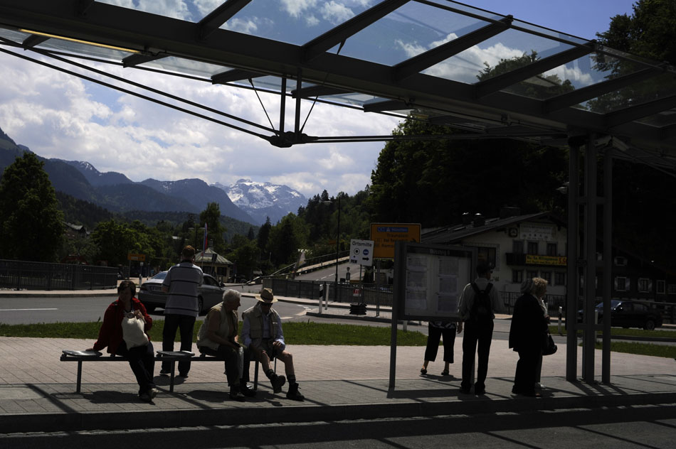 A mountain looms in the background as patrons await a bus on Tuesday, May 25, 2010, at the Berchtesgaden train station.
