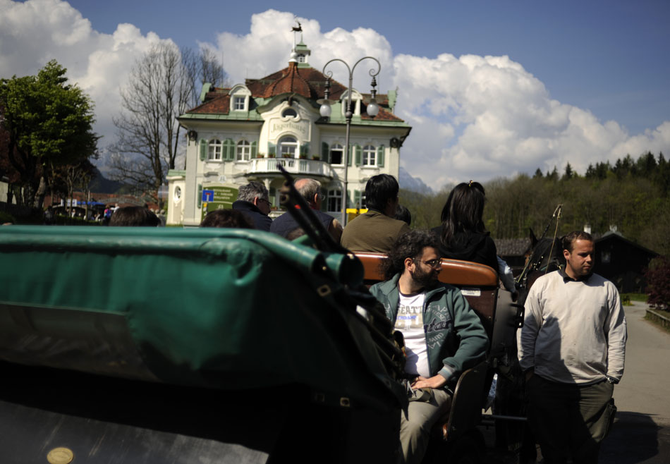 A horse carriage driver, right, waits for a customer to climb into the buggy for a ride to Schloss Neuschwanstein on Sunday, May 23, 2010, in Schwangau, Germany. Tourists wishing to avoid a 30-minute walk can pay for a carriage ride up the mountain to the castle.