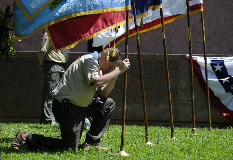 Boy Scouts Troop 408 scoutmaster Brian McGill bows his head in prayer while holding a flag during a ceremony marking the 60th Anniversary of the start of the Korean War at the Texas Korean War Veterans Memorial on Friday, June 25, 2010.