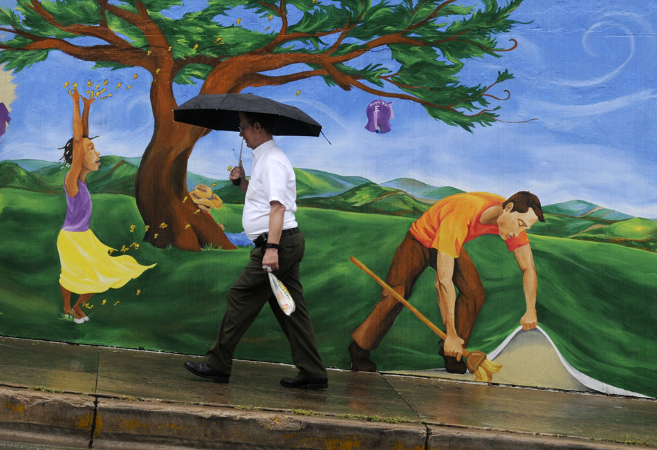 A man makes his way past a Hickory Street Bar & Grill mural in the rain on Eighth Street near the intersection of Congress Avenue on Wednesday, June 9, 2010. Downtown was a sea of umbrellas  as an early morning shower sent pedestrians scrambling for their rain gear to keep dry.