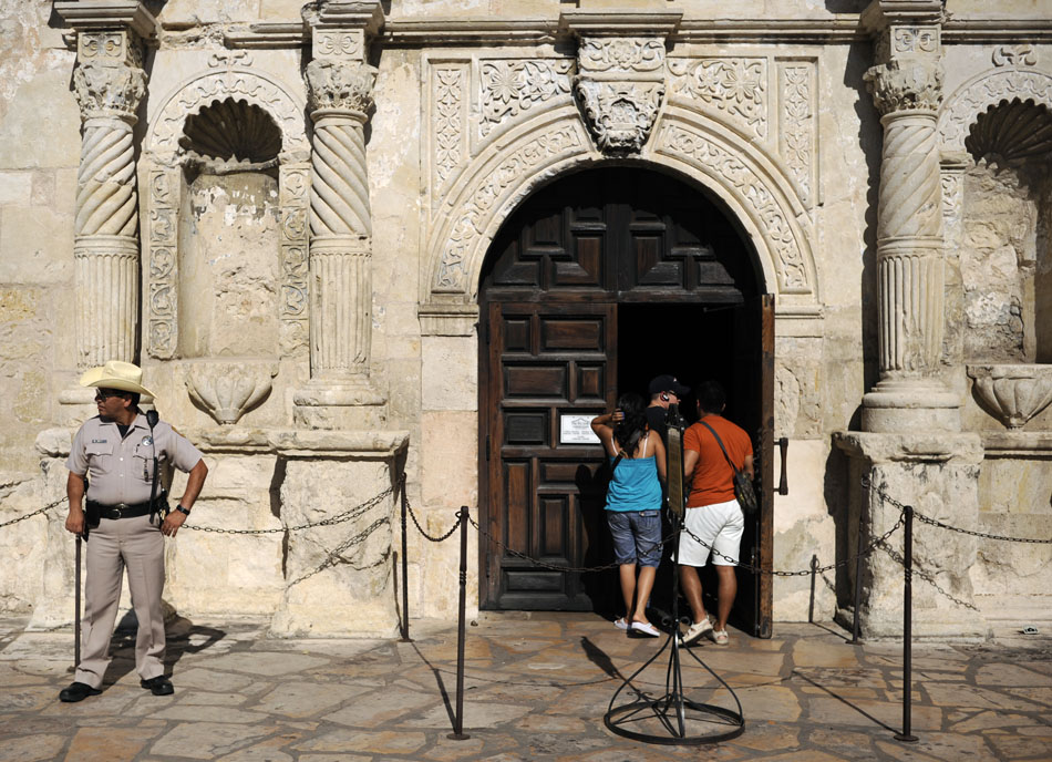 As tourists enter the Alamo, an Alamo Ranger, left, keeps watch on Saturday, July 31, 2010, in San Antonio, Texas.
