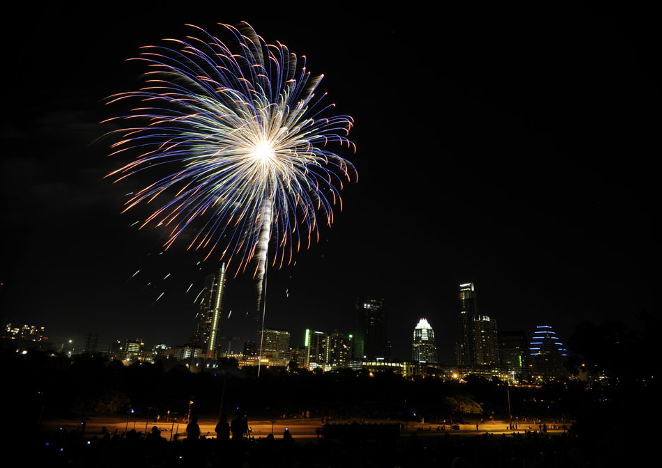 Fireworks explode over Town Lake in front of the Austin skyline as seen from Auditorium Shores Park on Sunday, July 4, 2010.