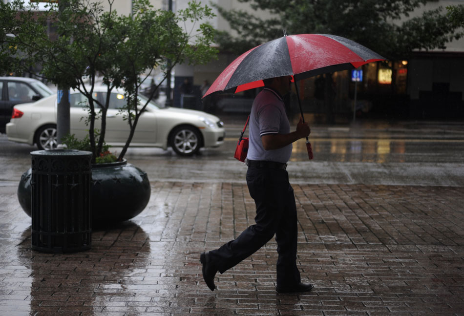 A man walks through the rain along Congress Avenue downtown on Friday, July 2, 2010.