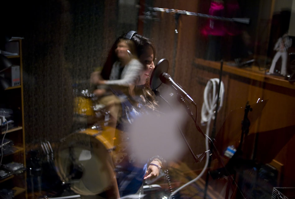 Sydney Dotson prepares to put down a vocals track in the studio as her band, the Explosion of the Minds, are reflected in a window during a session of Rock Camp USA at the Austin School of Music on Wednesday, July 21, 2010.