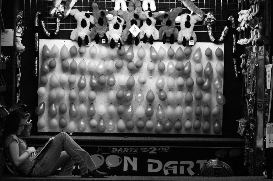 A carnival worker does her homework as she waits for customers during the Fall Festival on Thursday, Sept. 9, 2010, in Elmwood, Ill.