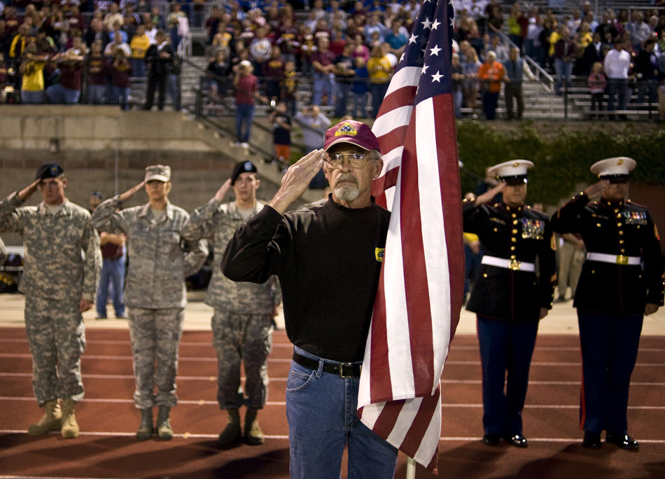 Terry Hicks, of Galsburg, Ill., salutes as taps are played to honor former East Peoria High School students who have been killed in the military during patriotic night ceremonies before a East Peoria-Washington football game on Friday, Sept. 10, 2010, in East Peoria. Hicks served with the Army in Vietnam.