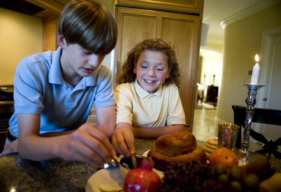 Alena Fishkin, right, age 9, dips apples slices into a bowl of honey with her brother, Grant, age 12, as their mother prepares a Rosh Hashanah meal on Wednesday, Sept. 8, 2010, at their Peoria home. Many Jews eat apples and honey together to ensure a sweet new year. The Fishkins will serve a buffet-style Rosh Hashanah meal at their home on Thursday evening for about 30 people, Ladona Fishkin said.