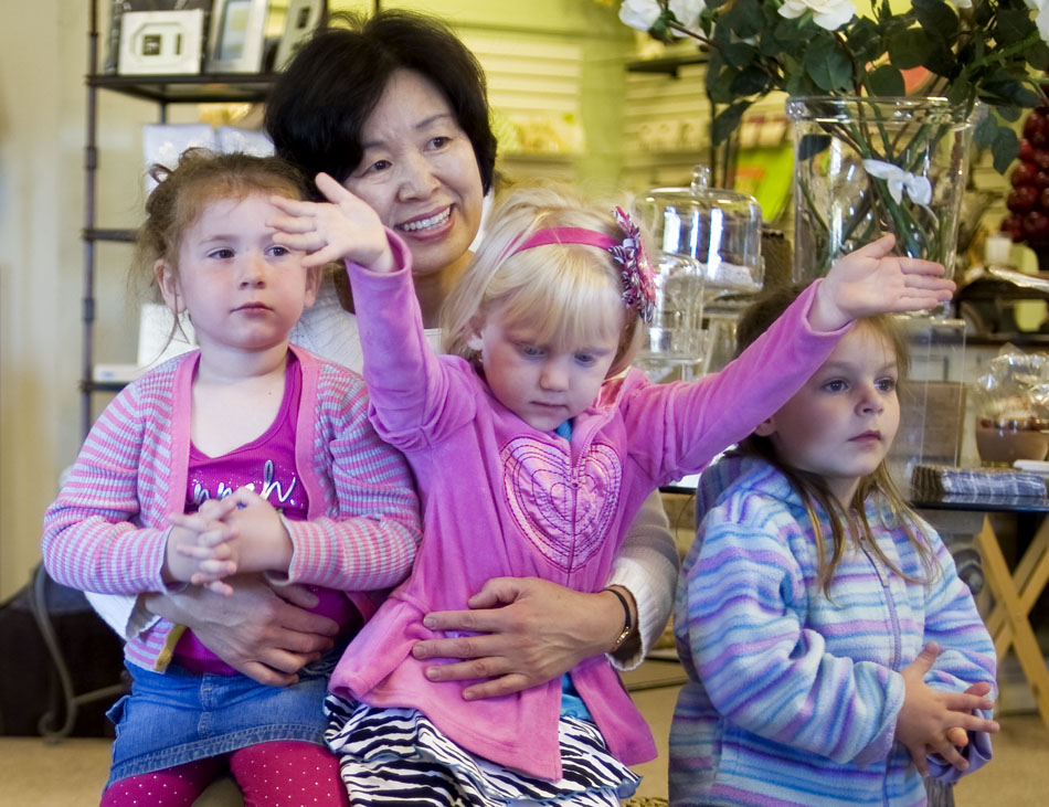 Sue Kim, the director of the Montessori Academy of Peoria, sits with Ava Woker, left, age 3, and Ashley Paul, right, age 3, as Savannah Milaccio, age 4, visually shows how big of a snow ball she made during a reading of "The Snowy Day" on Thursday, Oct. 7, 2010, at the Bronze Frog. The reading was part of Read for the Record, a campaign to increase early literacy by reading the same book at the same time (11 a.m.) on Thursday across the  country.