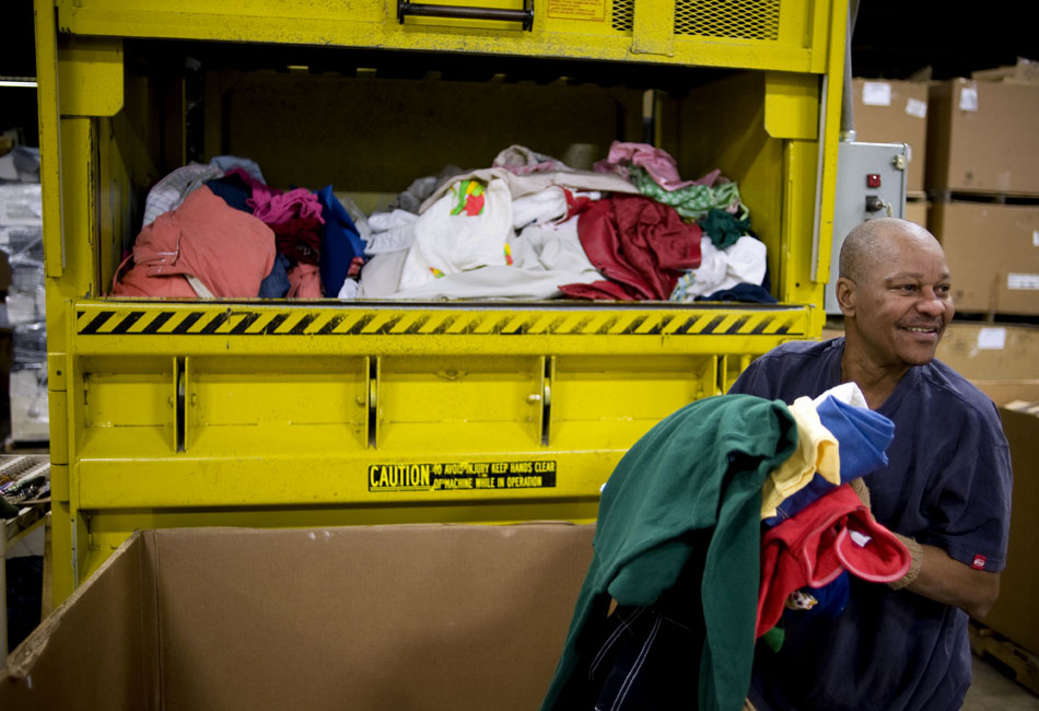 Donnell Lewis loads clothes into a compactor on Monday, Nov. 15, 2010, at the Goodwill Logistics Center in East Peoria. Not all items donated to the store can be resold due to quality. Clothes that cannot be sold are compacted and disposed of.