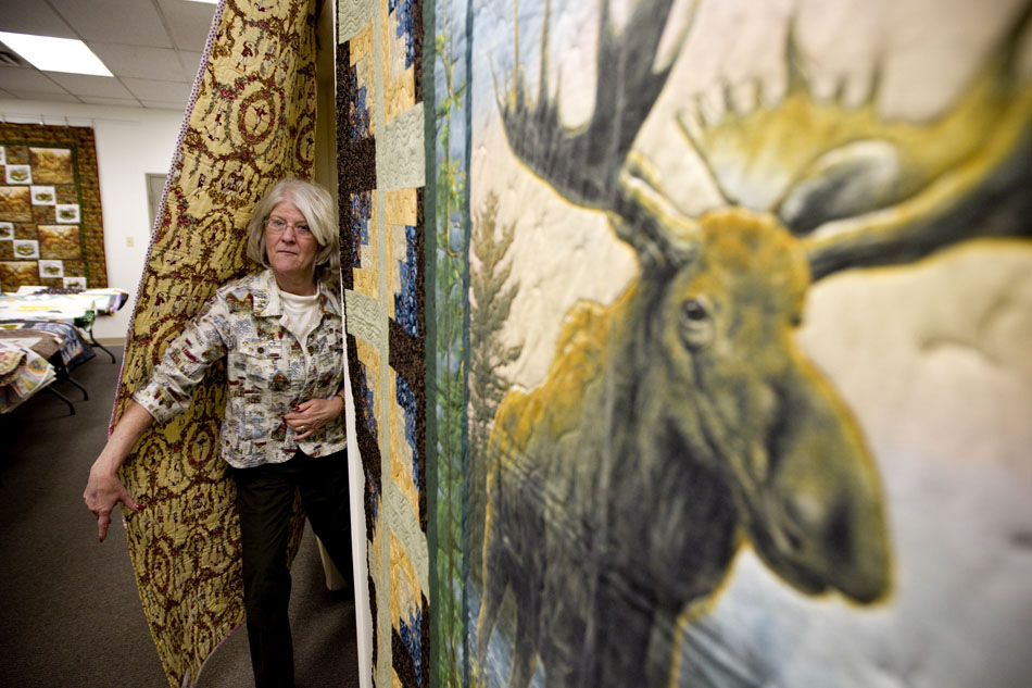Brenda Salverson, owner of the Quilted Corner, emerges from behind a quilt covering the entryway to her office on Tuesday, Jan. 18, 2011, at the downtown store. The store is selling 30 machine and hand-made quilts from local quilter Sarah May Robinson through Jan. 22.