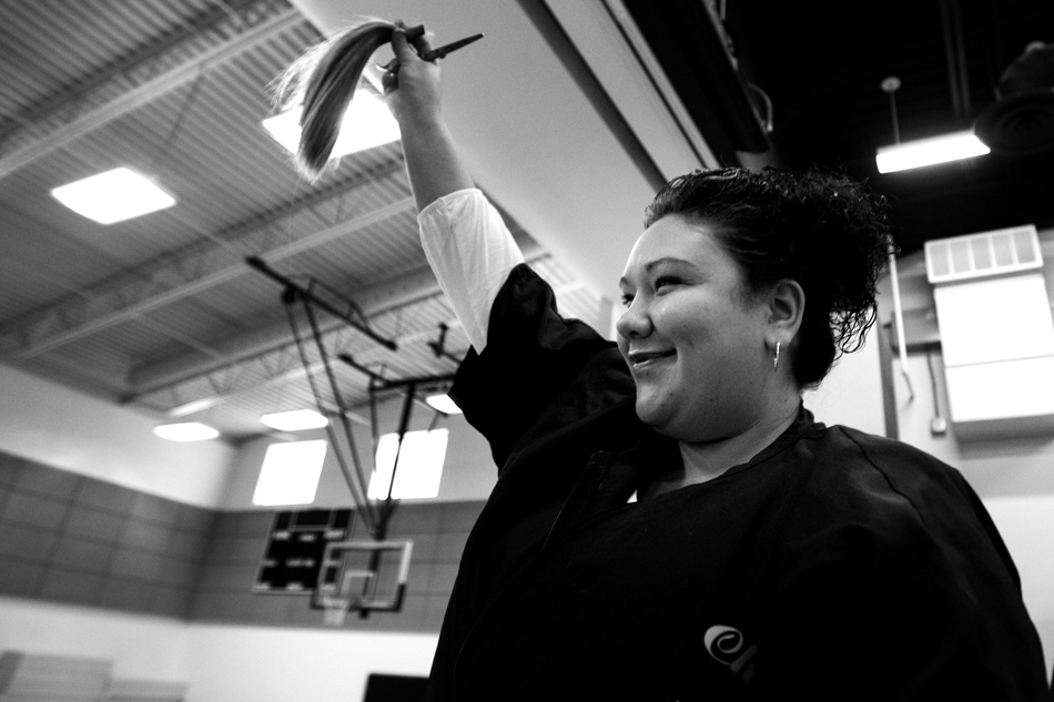 Cheeks Salon student Jerrica Jenson holds up the first lock of hair cut as three students at Sunrise Elementary donate during a school assembly on Friday, Jan. 28, 2011, at the school.