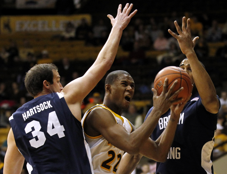 Wyoming forward Amath M'Baye (22) reacts as he splits two BYU defenders en route to the basket during a game on Tuesday, Feb. 2, 2011, in Laramie, Wyo. BYU won 69-62.