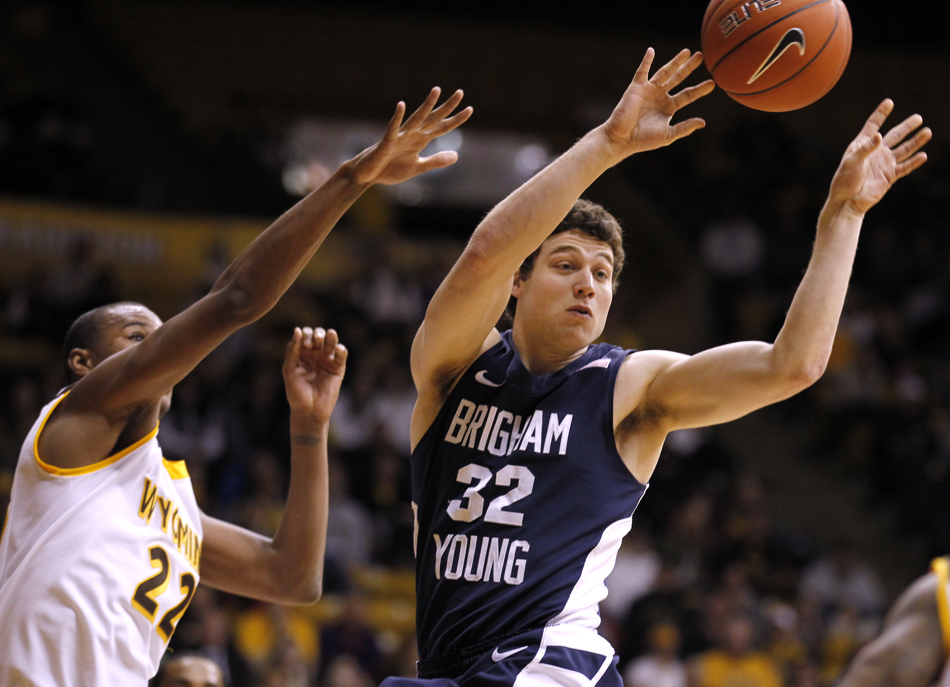 BYU guard Jimmer Fredette (32) kicks the ball out to a teammate on the perimeter in front of Wyoming forward Amath M'Baye (22) during a game on Tuesday, Feb. 2, 2011, in Laramie, Wyo. BYU won 69-62.