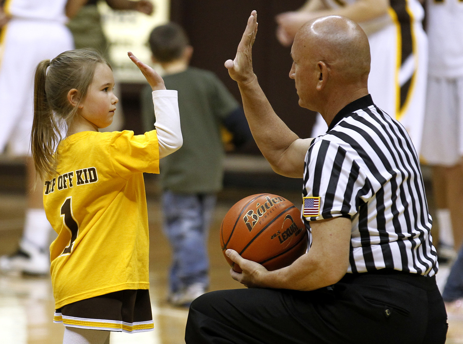 Alexia Lucero, age 5, gives a high five to an official before the start of a women's basketball game against Utah on Wednesday, Feb. 16, 2011, at the University of Wyoming in Laramie, Wyo. The youngster served as the "tip off kid" before the game.