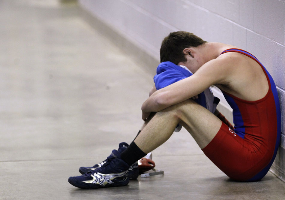A wrestler sits alone in a hallway outside the locker rooms following a defeat in the Wyoming high school state wrestling tournament on Saturday, Feb. 26, 2011, in Casper, Wyo.