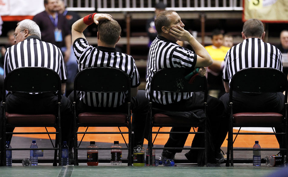 An official watches the action on a mat across the arena as he sits with his colleagues between matches during the Wyoming high school state wrestling tournament on Saturday, Feb. 26, 2011, in Casper, Wyo.