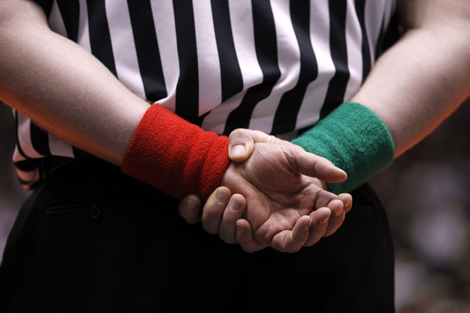 An official rests his hands behind his back as he watches a finals match during the Wyoming high school state wrestling tournament on Saturday, Feb. 26, 2011, in Casper, Wyo. Officials use red and green wristbands to easily award points to wrestlers with corresponding colors during the matches.