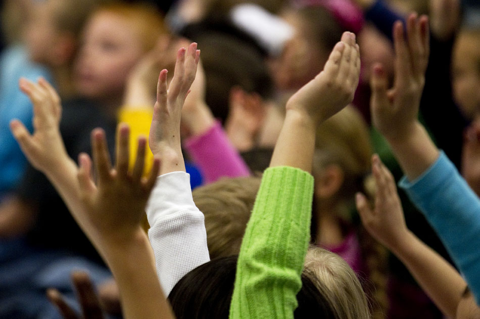 Youngsters raise their hands to show a school administrator  that they are listening before the start of an African acrobatics assembly on Friday, March 18, 2011, at Freedom Elementary in Cheyenne.