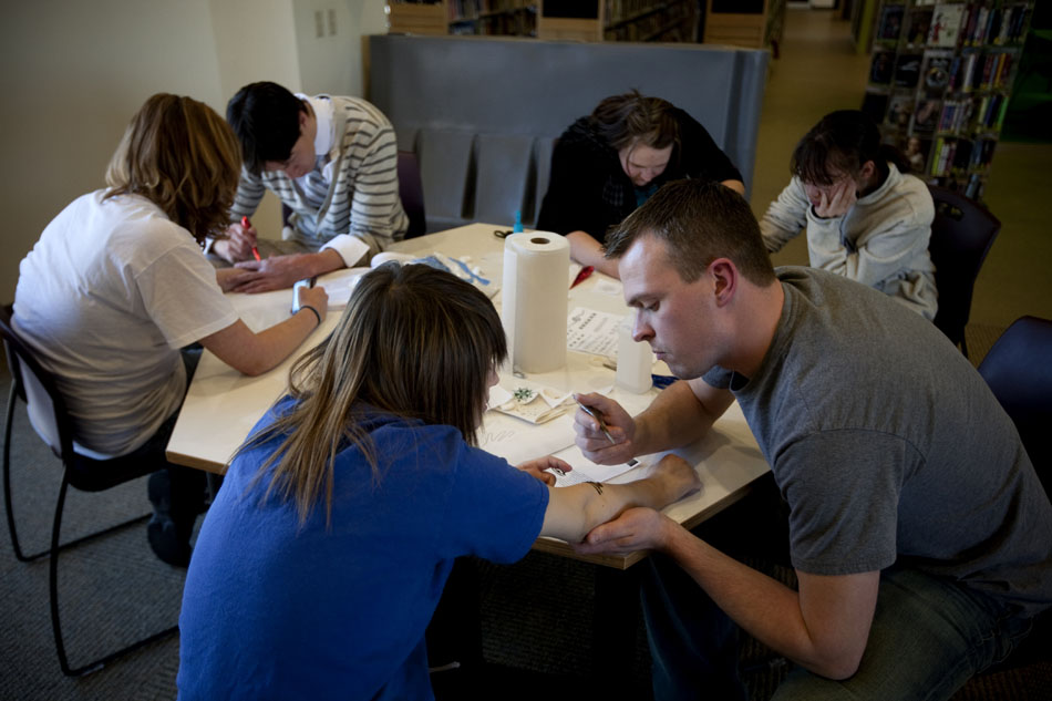 Volunteers including Tristan Janini, foreground, paint henna tattoos on Wednesday, March 23, 2011, in the teen lounge at the Laramie County Library in Cheyenne.