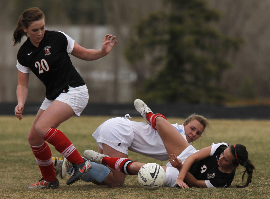 Cheyenne Central's Makena Cameron, right, falls to the pitch with Cheyenne East's Brittney Rexius as Central's Auri Fermelia (20) plays the ball during a high school girl's soccer game on Friday, March 25, 2011, at Cheyenne East High School.