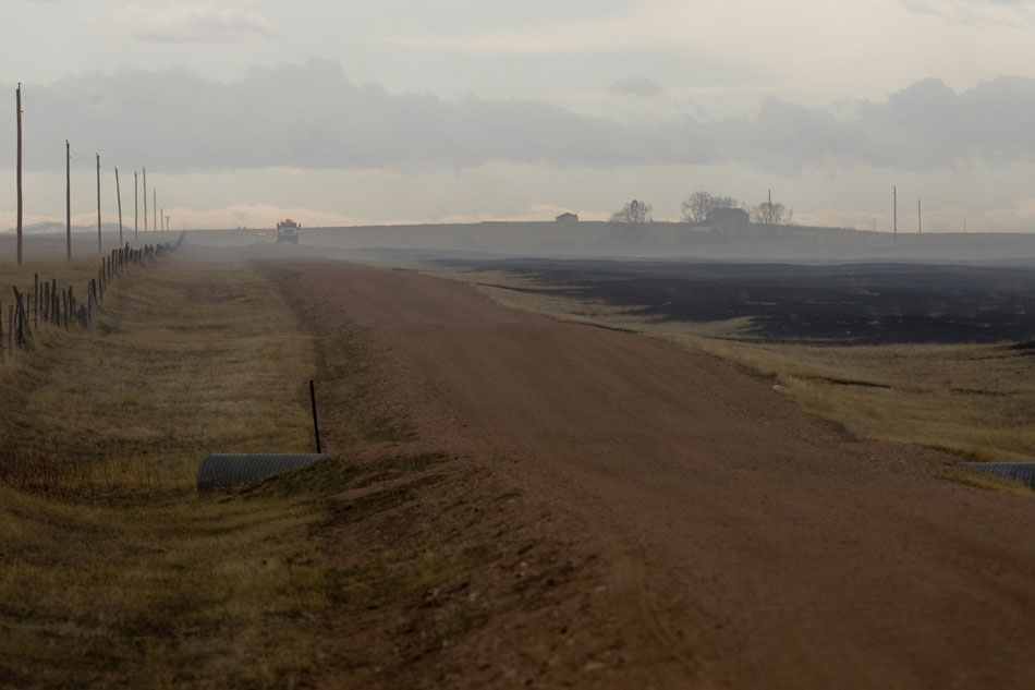 A tanker truck sits in the smoke along Country Road 225 as a field smolders following a brush fire on Friday, April 1, 2011, north of Cheyenne.