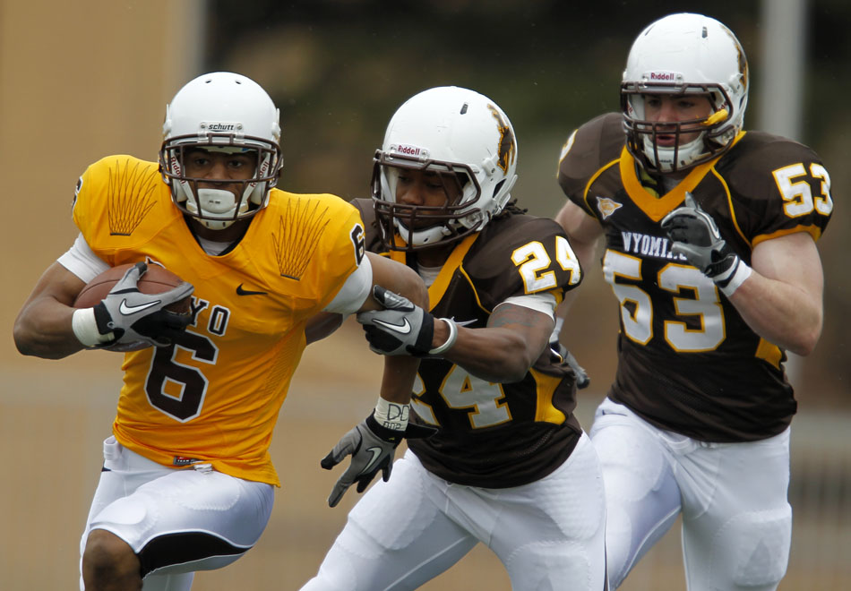 Wyoming wide receiver Robert Herron (6) darts away from teammate defenders Kenny Browder (24) and Alex Borgs (53) during Wyoming's Brown and Gold spring football game on Saturday, April 9, 2011, in Laramie, Wyo. Gold won 14-13.