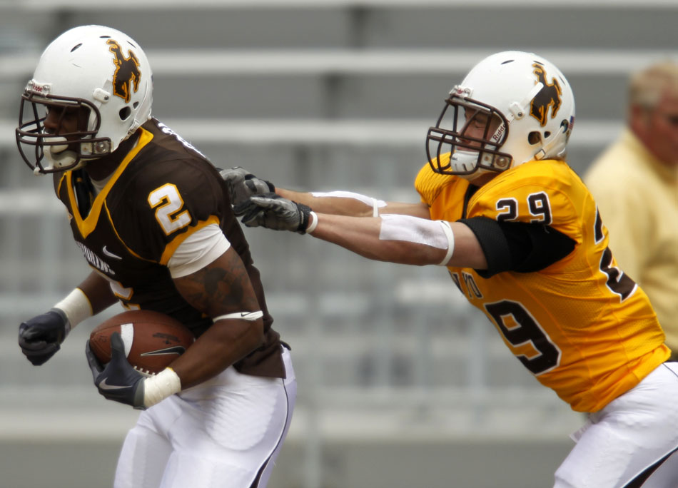 Wyoming strong safety Luke Ruff (29) makes a last-ditch effort to tackle teammate wide receiver Mazi Ogbonna (2) near the goal line during Wyoming's Brown and Gold spring football game on Saturday, April 9, 2011, in Laramie, Wyo. Gold won 14-13.