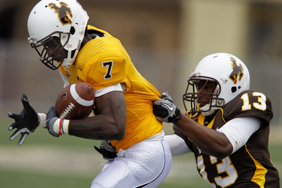 Wyoming's Jonathan Aiken (7) works to secure the ball after a catch as teammate Darrenn White (13) tackles him during Wyoming's Brown and Gold spring football game on Saturday, April 9, 2011, in Laramie, Wyo. Gold won 14-13.