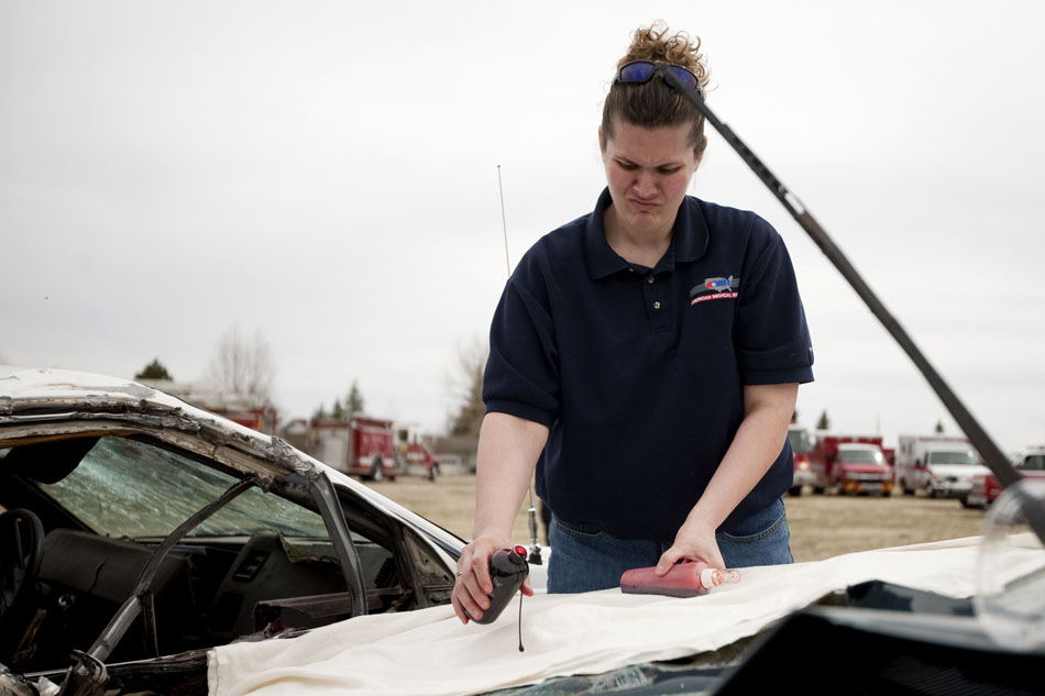 A first responder grimmaces as she spreads fake blood onto the hood of a car before a drunk crash demonstration on Tuesday, April 12, 2011, at Okie Blanchard Stadium. The demonstration coincides with East's prom this Saturday.