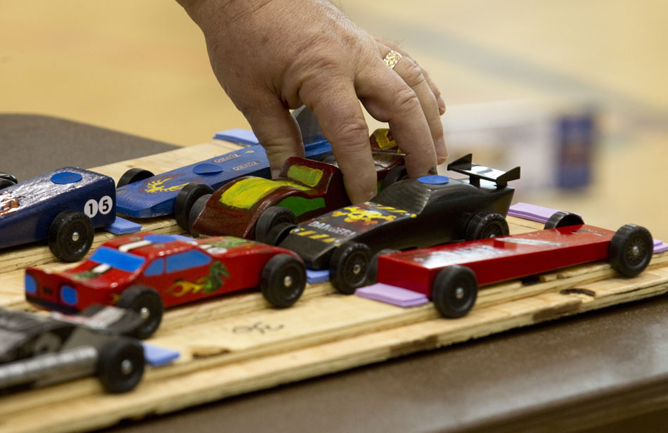 A volunteer sets down a pinewood derby car after a heat on Saturday, April 23, 2011, at Storey Gym.