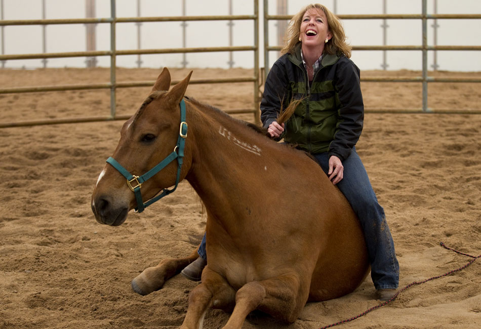 Kathi Wilson, of Cheyenne, laughs as she performs a trick with her horse, Snickers, on Friday, April 29, 2011, at the Riata Ranch near Cheyenne. Snickers, a wild-born horse, was adopted from the Steve Mantle Training Facility in 2003. Several people came to the ranch on Friday to view yearling mustangs that will be auctioned off by the Bureau of Land Management starting at 10:30 a.m. on Saturday morning.
