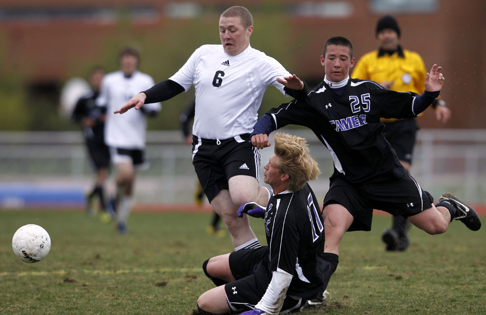 Gillette's Brandon Swan, center, falls to the pitch as his teammate Jasen Scalzo (25) plays the ball with Cheyenne East's Sam Devine during a boy's soccer regional game on Thursday, May 12, 2011, at Cheyenne South High School.