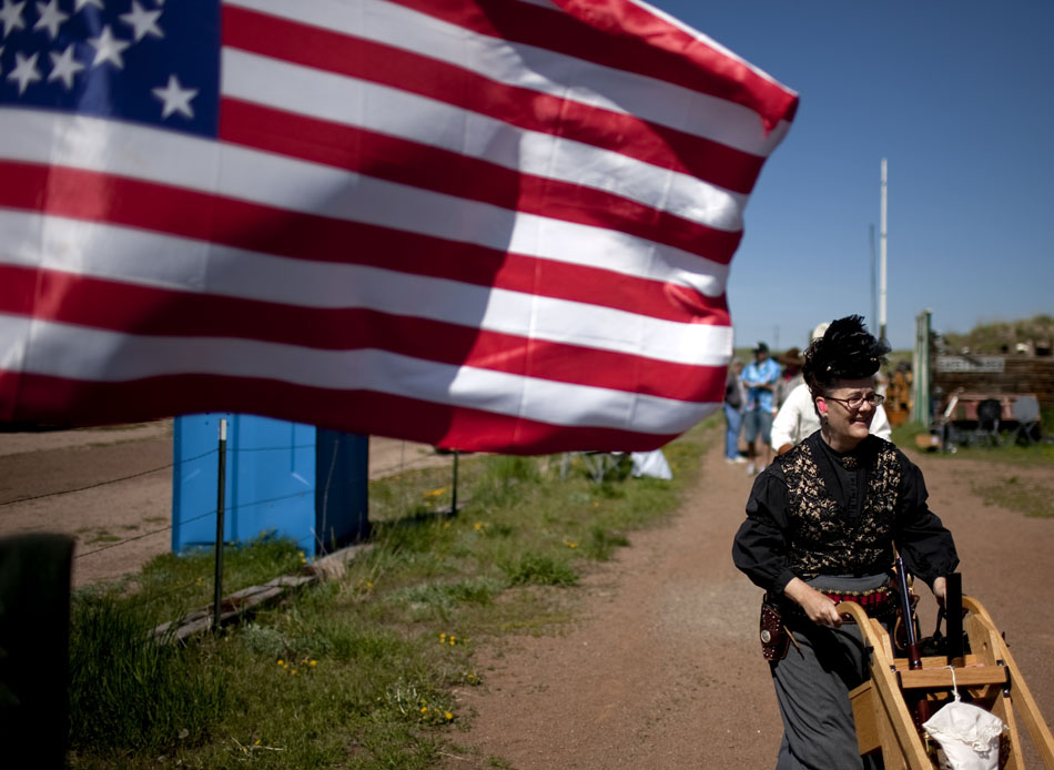 A Cheyenne Regulators member uses a wheeled cart to transport her weapons from one shooting bay on Saturday, June 4, 2011, at the range west of Cheyenne. During a cowboy shoot, each posse switches shooting bays after a rotation through the stall.