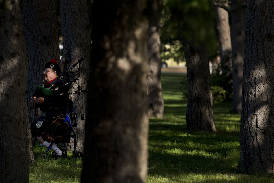 Bob McLelland watches as fellow bagpiper Dana Anderson, not pictured, warms up in the woods near a replica Vietnam Wall on Thursday, June 23, 2011, in Lions Park. McLelland and Anderson played "Amazing Grace" on the bagpipes during an opening ceremony for the replica wall.