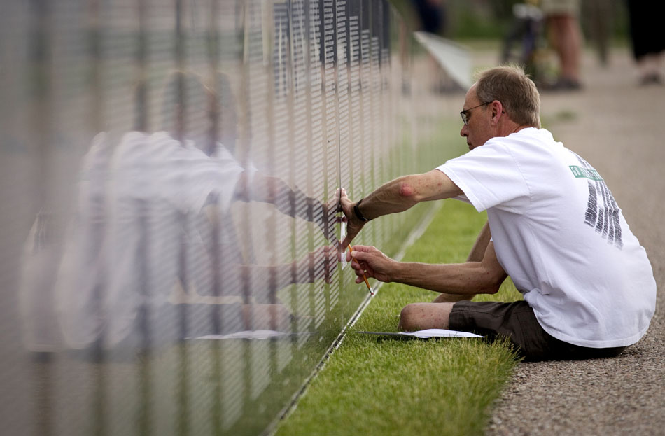 Thomas Johnson, of Cheyenne, sketches the name of Richard Estrada, a hometown friend from Bridgeport, Neb., off of a replica Vietnam Wall after an opening ceremony on Thursday, June 23, 2011, in Lions Park. The wall will be on display in Lions Park through Sunday.