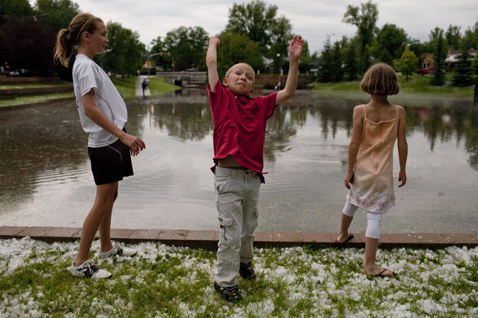 Cullen Gienapp, 8, center, reacts as he tosses a piece of hail over his head into the flood waters on Tuesday, July 12, 2011, at Pando Park in Cheyenne. He, along with his siblings Abigail, 12, and Ella, 8, tossed hail into the water with other youngsters at the park after a severe thunderstorm swept across the area.
