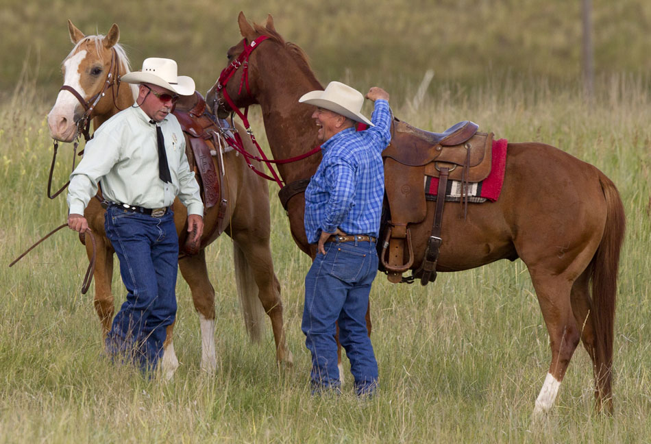 A cowboy shares a laugh as he talks to a fellow cowboy before the start of the Cheyenne Frontier Days cattle drive on Sunday, July 17, 2011, north of Cheyenne.