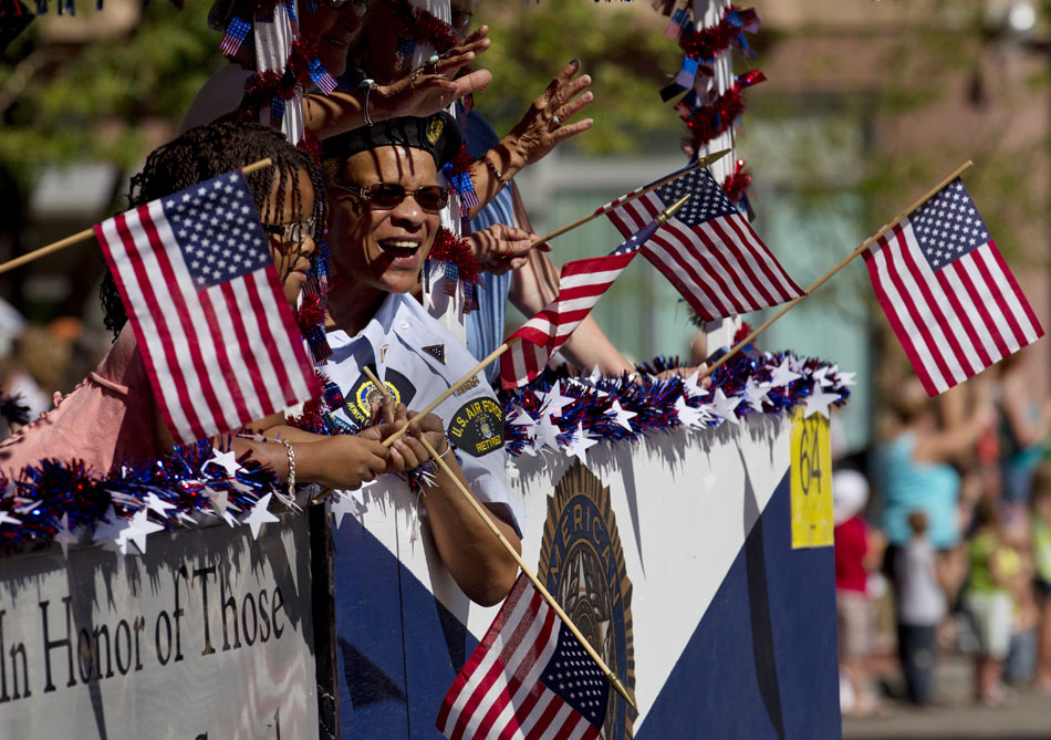 A woman waves to the crowd amongst American flags atop an American Legion float during the Cheyenne Frontier Days rodeo on Satruday, July 23, 2011, in downtown Cheyenne.