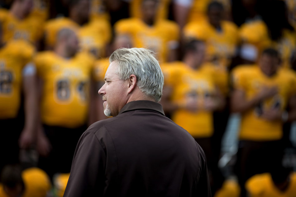 Wyoming coach Dave Christensen watches as his team lines up for a photo during the University of Wyoming's media day on Saturday, Aug. 6, 2011, at Memorial Stadium in Laramie.