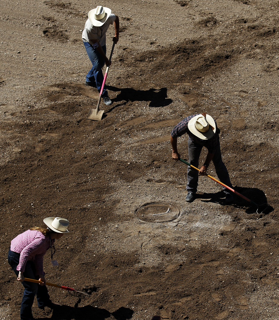 Volunteers use rakes and shovels to smooth down dirt in the arena during the first go of barrel racing on Tuesday, July 19, 2011, at Frontier Park.